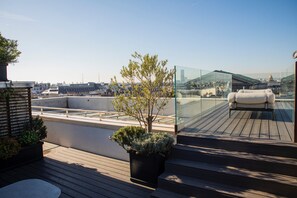 A rooftop terrace with a glass balustrade, a sofa, and potted plants. - Hôtel de Pourtalès (Paris)