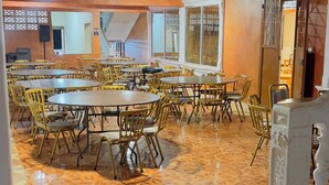 Un'ampia sala da pranzo con diversi tavoli rotondi e sedie, un pavimento decorato e un soffitto alto con travi a vista.