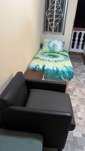 A small room with a bed, a sofa, and a window with a metal grille. - Brownerts Resort (Freetown)