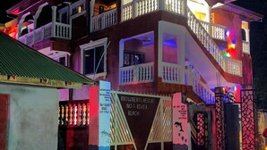 Un edificio a due piani con balconi, una segnaletica che indica un resort e un ingresso con cancello.