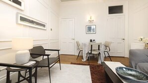Une chambre d’hôtel moderne dotée d’un coin repas, d’un canapé, d’une lampe et d’un lustre.