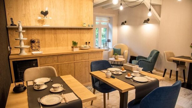 A dining area with a wooden counter, blue chairs, and a table set for two.