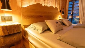 A cozy wooden room with a bed, pillows, and a nightstand with a lamp. - ad maiora baita walser chalet with spa (alagna valsesia)