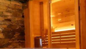 A wooden spa area with a stone wall and a hot tub. - ad maiora baita walser chalet with spa (alagna valsesia)