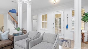 A modern living room with a staircase, white walls, and a blue accent wall. - La Madeleine Coastal Home Resort Pools Quiet Beach (Gulf Shores)