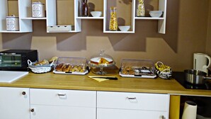 A kitchen with white cabinets, a microwave, and various food items displayed on the counter. - affittacamere arancio (Lucca)