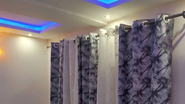 A room with a blue sofa, a curtain with a leaf pattern, and blue ceiling lighting. - Résidence le prestige (Kribi)