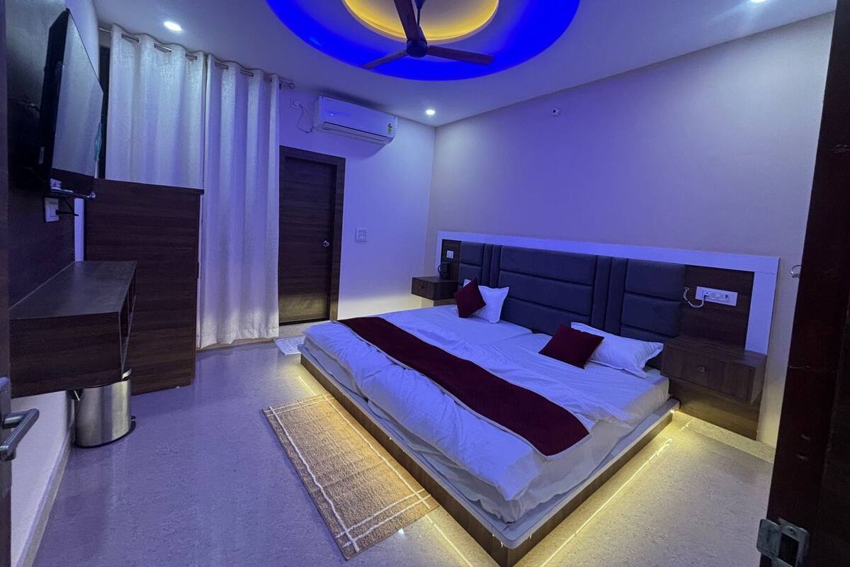 Une chambre moderne avec un lit, des tables de chevet, un bureau et un luminaire au plafond.