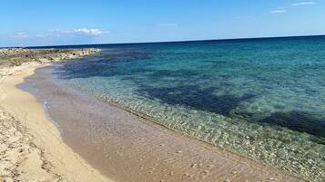 Una spiaggia con acque limpide e poco profonde e una battigia sabbiosa.