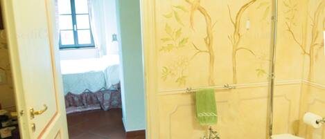 A bathroom with a toilet, bidet, and sink. There is a towel hanging on the wall and a window in the background.