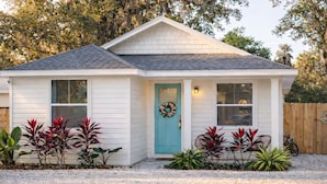 A single-story house with a front porch, a turquoise door, and a wreath. - Sunshine Duo: Two Coastal Homes Blocks Apart, Sleeps 13, 1mi to Downtown (St. Augustine)