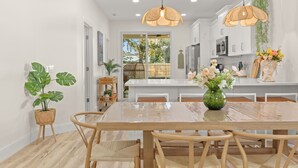 A modern kitchen with white cabinets, a large island, and pendant lighting. - Sunshine Duo: Two Coastal Homes Blocks Apart, Sleeps 13, 1mi to Downtown (St. Augustine)