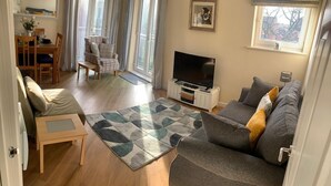 Una sala de estar acogedora con un sofá, un televisor y un comedor con una mesa y sillas.