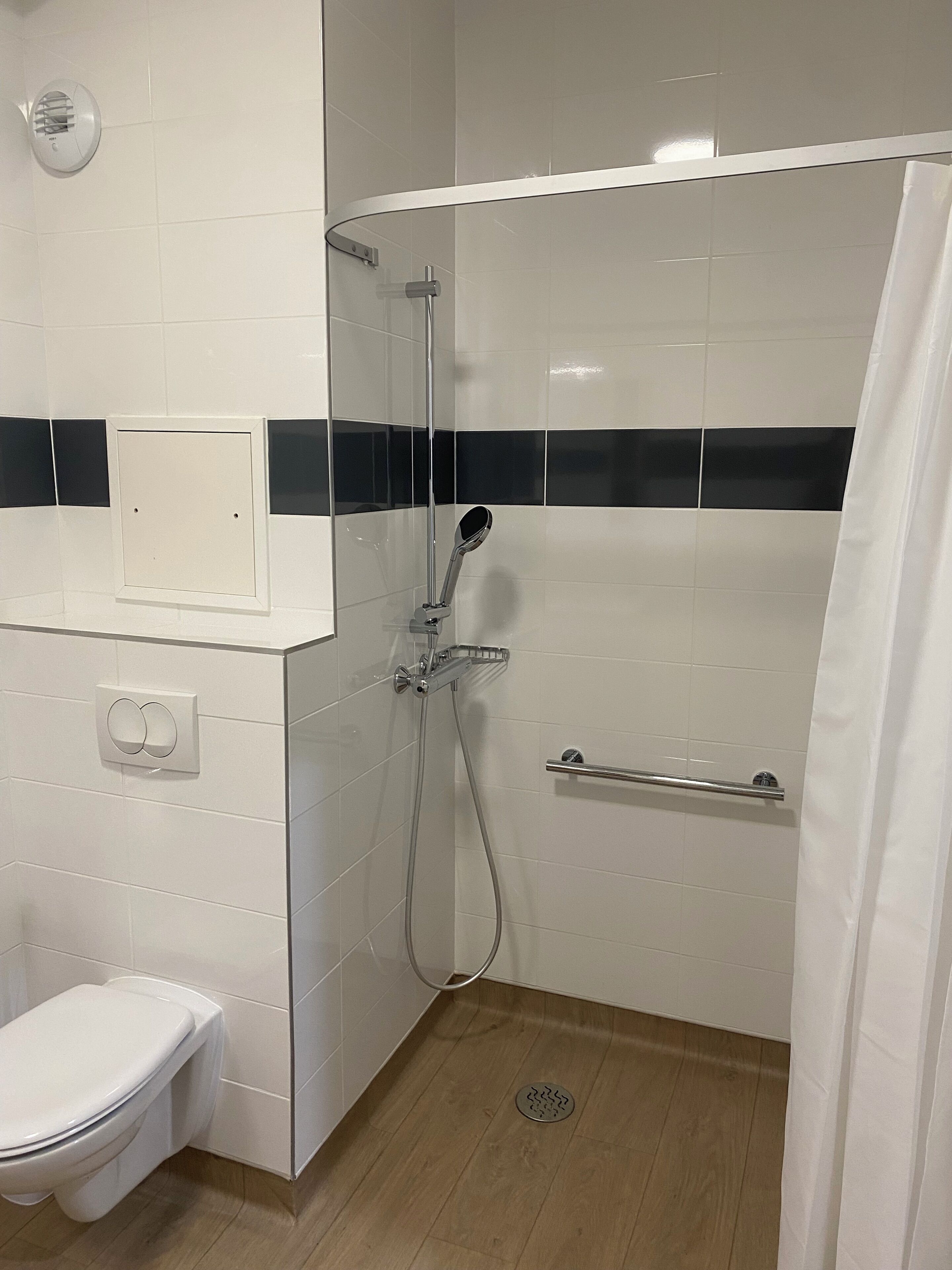 A shower with a glass door, a toilet, and a towel rack.