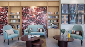 Una biblioteca moderna con dos sofás, una mesita de centro y estanterías llenas de libros.