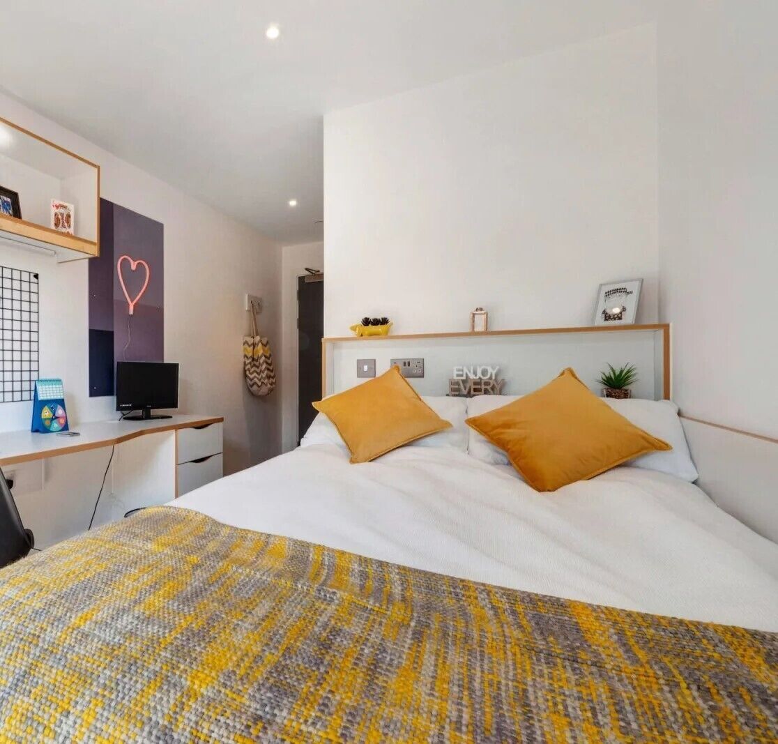 A modern bedroom with a bed, a desk, and a television.