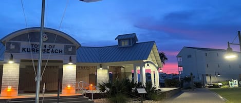 Un edificio con un letrero que dice 'Town of Kure Beach' y un asta con banderas.