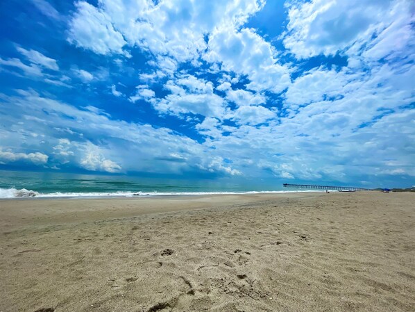 A beach with footprints, a pier, and the ocean. - Gorgeous 4 BR with Ocean Views & Pool (Kure Beach)