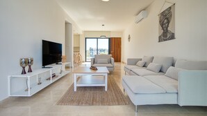 A modern living room with a flat-screen TV, a sofa, and a coffee table. - Avalon Gardens Villa 21 (Emba)