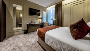 Habitación de hotel con una cama grande, un escritorio, un televisor de pantalla plana, una silla y un espejo.
