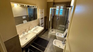 A modern bathroom with two sinks, a bidet, and a glass-enclosed shower. - Belvedere 18 (Bagno A Ripoli)