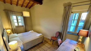 A cozy bedroom with a bed, bedside table, chair, and a small table with a lamp. - Belvedere 18 (Bagno A Ripoli)