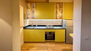 A compact kitchen with yellow cabinets, a gas stove, and a built-in oven. - Belvedere 18 (Bagno A Ripoli)