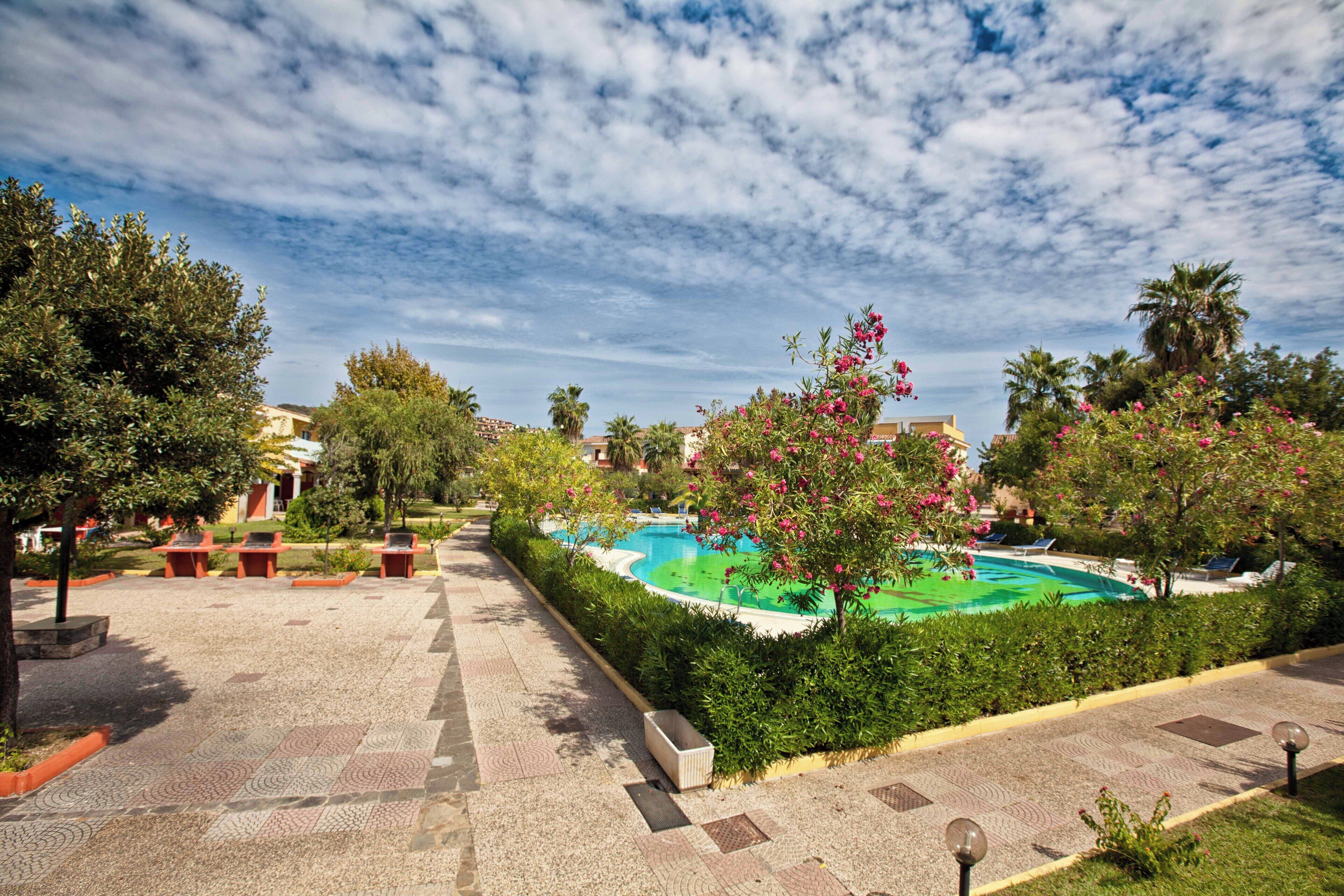 A courtyard with a swimming pool, seating areas, and lush greenery.
