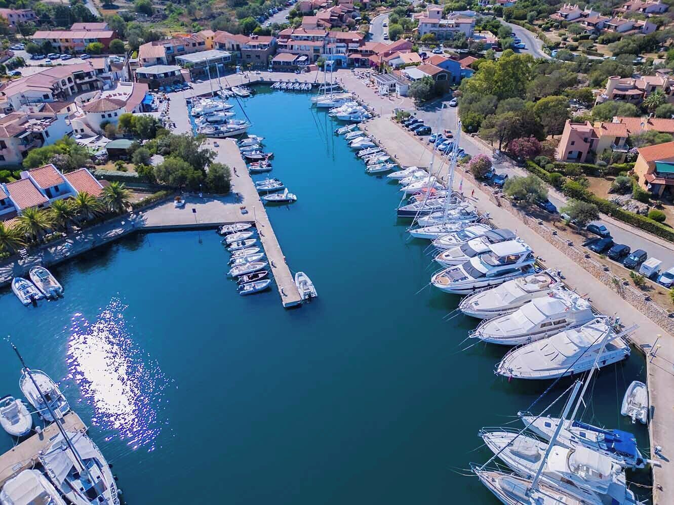 An aerial view of a marina with boats docked along the waterfront, surrounded by residential buildings.