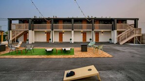 A multi-story motel with outdoor seating and a flat-screen TV.
