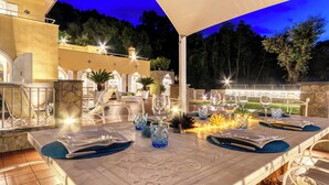 An outdoor dining area with a marble table, white chairs, and blue placemats. - Villa Eva | Sea View Luxury Retreat with Pool, Spa & Terraces in Sorrento (Campania)