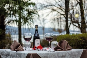 Mesa al aire libre con una botella de vino, dos copas, un tenedor y un cuchillo.