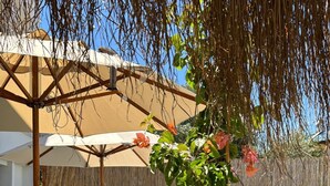 A poolside area with lounge chairs, a pergola, and a potted plant with pink flowers. - Güzergah Urla (Urla)