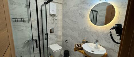 A modern bathroom with a glass shower enclosure, a toilet, a sink with a mirror, and a towel rack.
