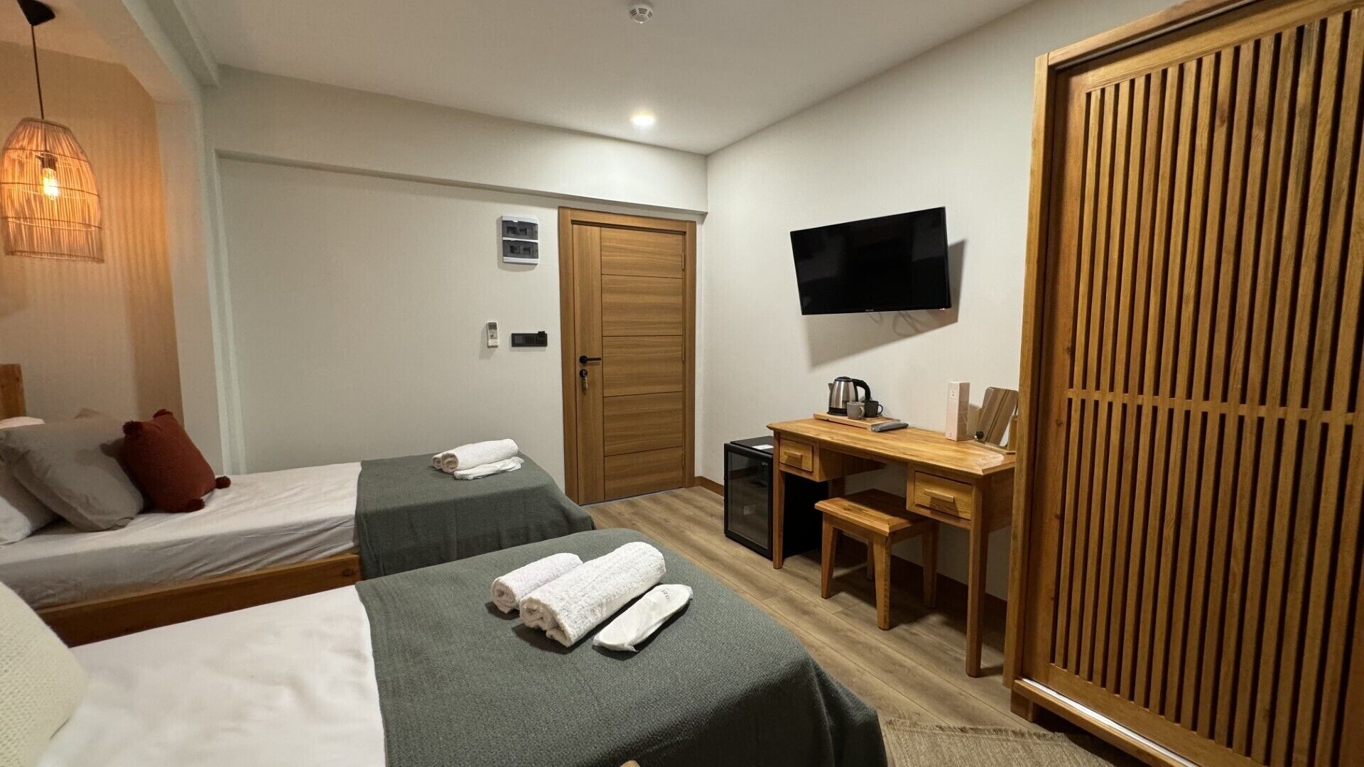 Habitación de hotel con dos camas, un escritorio, un televisor y un armario.
