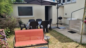 Un patio con mobiliario exterior, una parrilla y una zona cubierta con mesa y sillas.