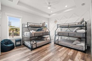 A room with two bunk beds, a bean bag chair, a small table, and a window with blinds.