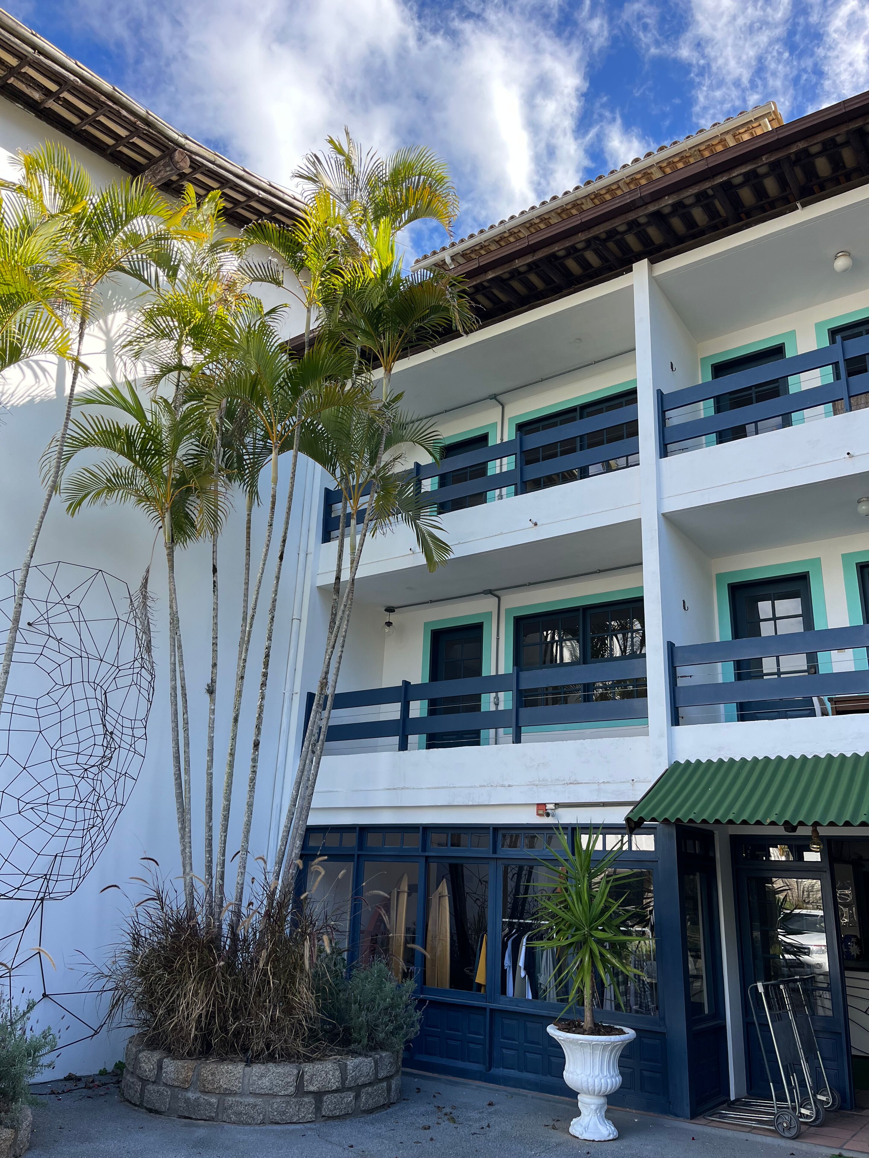 A multi-story building with balconies, a garage, and a potted plant in the foreground.
