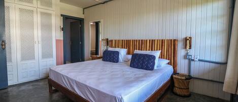 A bedroom with a wooden bed, white walls, and a wooden headboard.