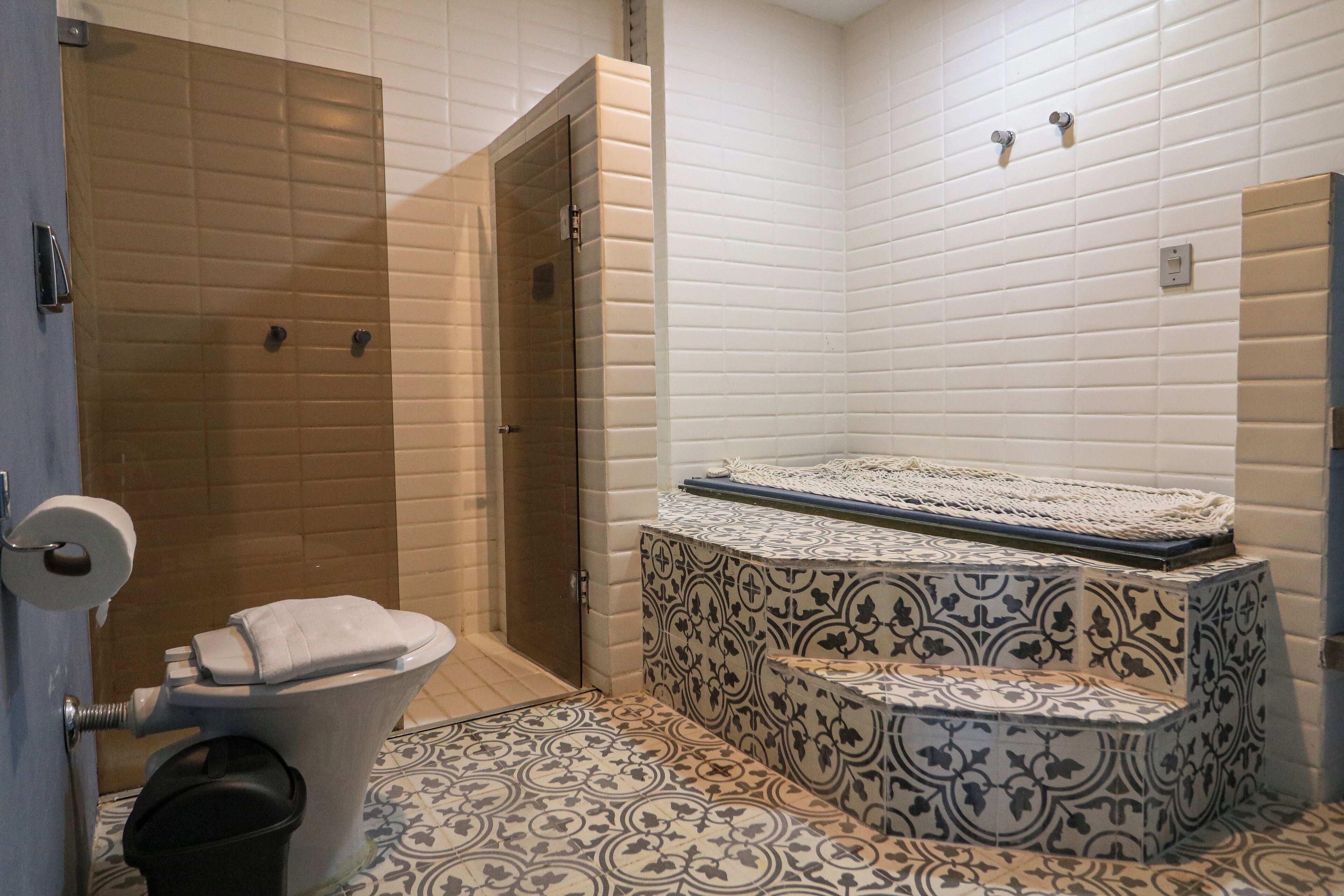 A bathroom with a shower, toilet, and a bathtub with a patterned tile design.