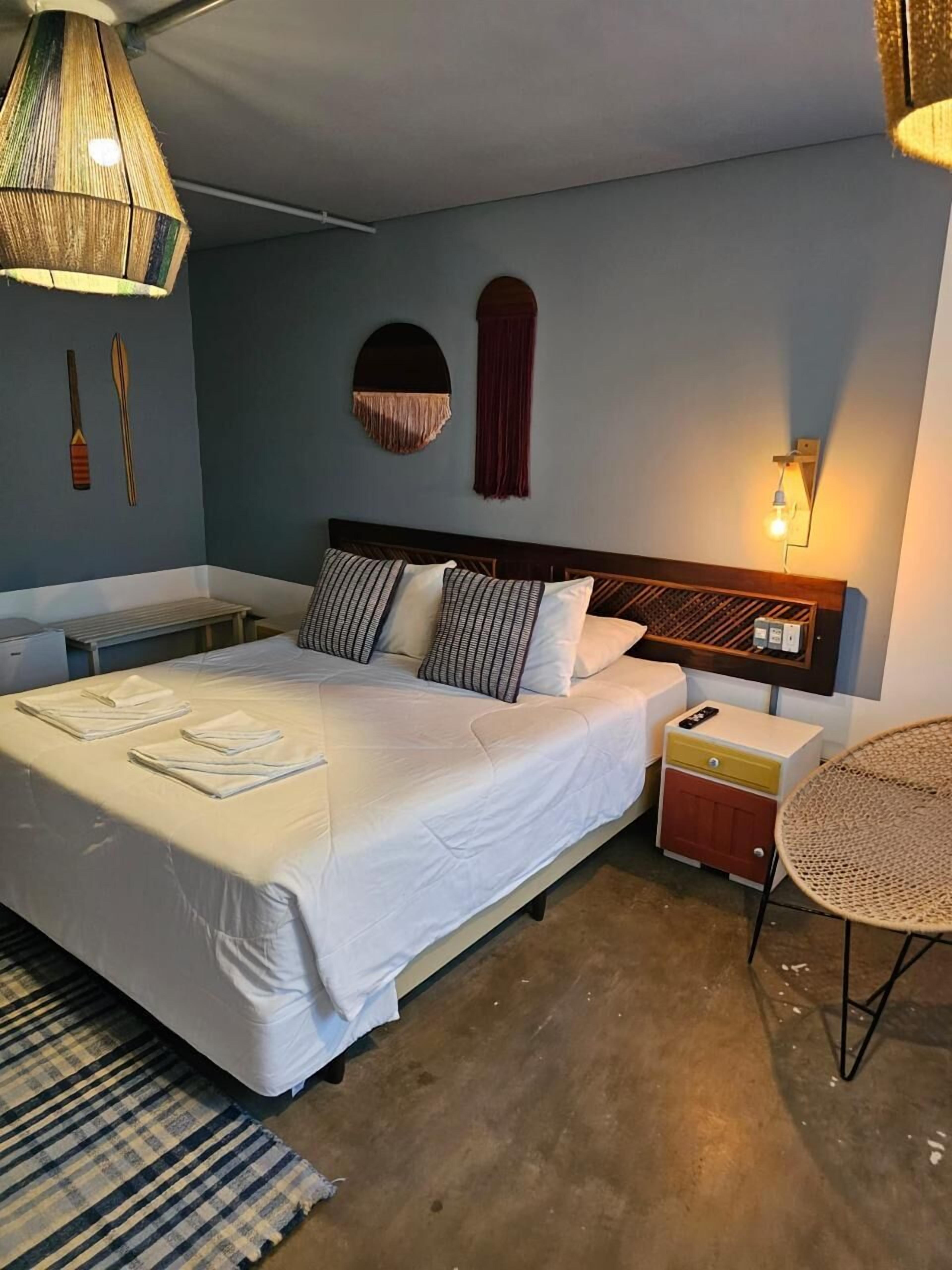 Un dormitorio con cama, mesita de noche, lámpara y una mesa redonda.