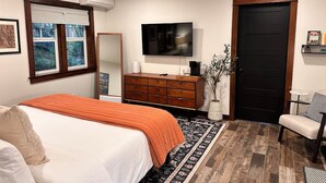 A bedroom with a bed, dresser, TV, and a door. - Charming Creekside Studio Near Ferries to Seattle (Port Orchard)