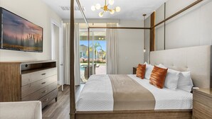 Un dormitorio con una cama grande, un televisor en la pared, un aparador de madera y vistas al exterior.
