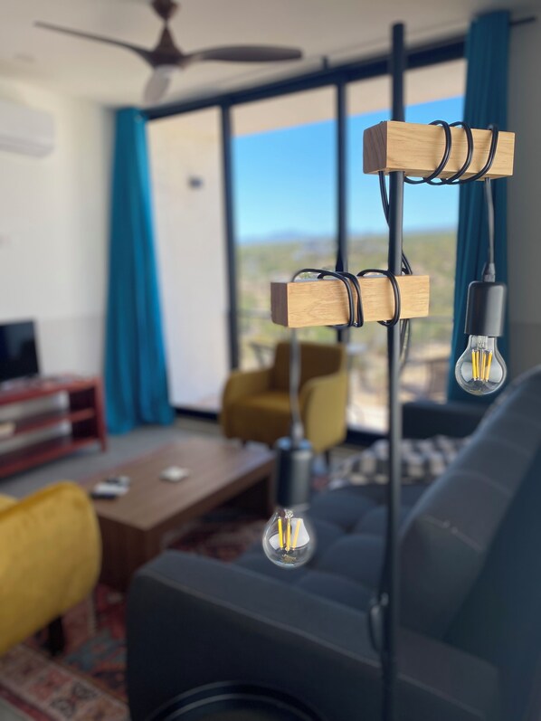 A modern living room with a ceiling fan, a sofa, a coffee table, and a view of the outdoors. - Charming 2-bedroom condo with Jacuzzy, WiFi, AC in welcoming El Sargento (El Sargento)