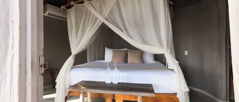 A bed with a canopy, a bedside table, and two bottles.