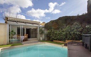 Relax in a serene backyard with a swimming pool, glass-enclosed patio, and lush greenery.