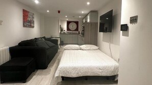 A compact hotel room with a bed, a sofa, a small kitchenette, and a bathroom. - Spacious1br-6guests-walktoshops-fastwifi (Royal Tunbridge Wells)