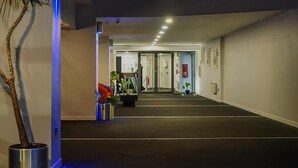 Eine Hotelhalle mit dunklem Teppich, einem Empfangsbereich und einer Pflanze im Topf.
