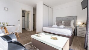 Una habitación de hotel moderna con cama, mesita de noche y escritorio con sillas.