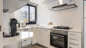Una cocina moderna con horno integrado, cafetera y ventana con vista a un paisaje urbano.